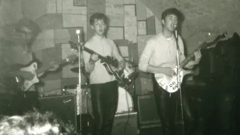 Tracks Ltd/Pa John Lennon and Sir Paul McCartney at the microphone, with George Harrison on guitar and a partially obscured Pete Best, the group's original drummer