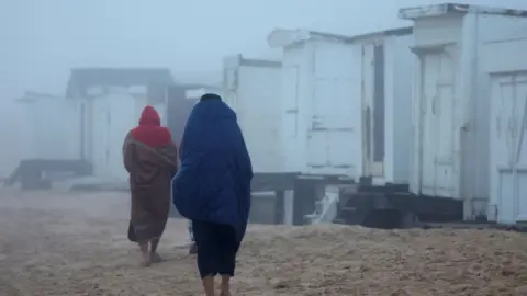 Reuters Migrants walking on a beach in Calais