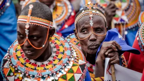 Getty Images A Samburu woman and Azimio La Umoja (One Kenya Coalition Party) supporters listen to presidential candidate Raila Odinga during a campaign rally in Suswa Grounds, Narok, Kenya on July 30, 2022, ahead of Kenya's general election