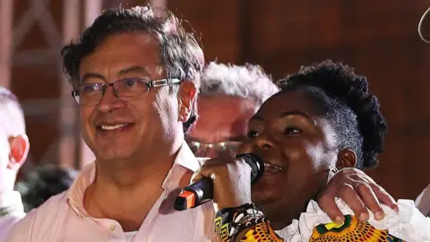 Getty Images Colombian presidential candidate left-wing Gustavo Petro, listens to Francia Marquez as she delivers a speech during a campaign rally in Cali, Colombia, May 19, 2022.