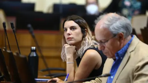 Maite Orsini Maite Orsini rests her chin on her hand, as she looks into the distance in parliament