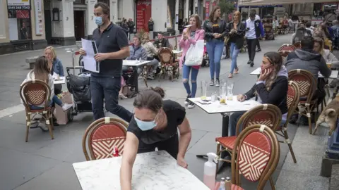 PA Media tables being cleaned at Di Maggio's outdoor restaurant area in Glasgow city centre.