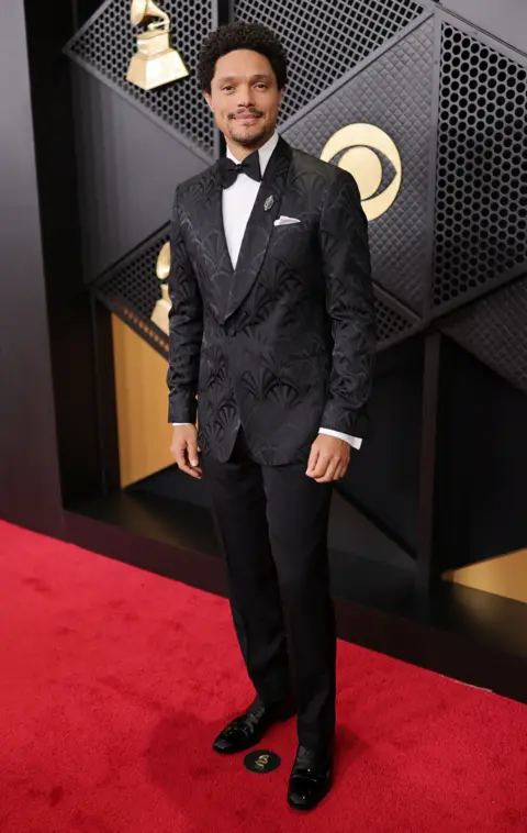 Getty Images Trevor Noah mira a la cámara mientras posa para una foto vistiendo un esmoquin en la alfombra roja de los Premios Grammy.