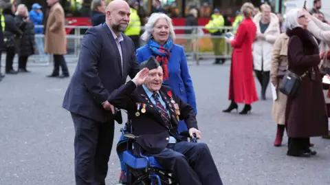 James Manning/PA Wire D-Day veteran and Royal British Legion Ambassador Bernard Morgan salutes as he arrives for the annual service. He is accompanied by two others.