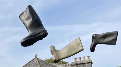 Three wellington boots in mid air