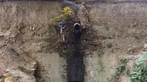Gloucestershire County Council Image shows a bridge which has cracked and a water pipe running through it.