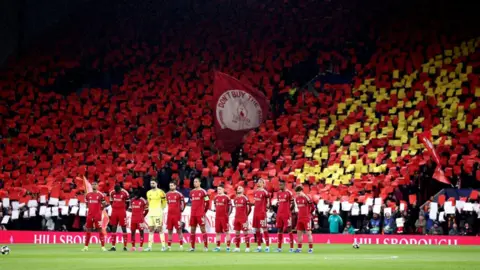 EPA/Shutterstock Liverpool team stand in a line on the pitch at Anfield to mark a minute's silence 