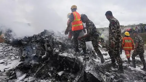 Getty Images Rescuers and army personnel stand at the site after a Saurya Airlines' plane crashed 