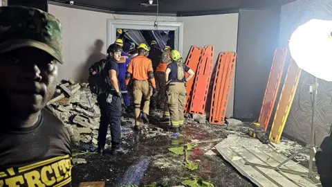 Getty Images Picture released by emergency services showing personnel of Civil Defence and firefighters inspecting the Jet Set nightclub after the collapse of its roof, in Santo Domingo, on April 8, 2025.