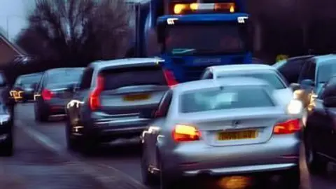 A blurred picture of cars and a lorry in a street, going both ways and bumper to bumper.