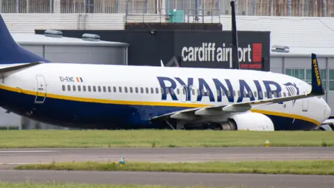 A Ryanair flight parked at Cardiff Airport, with the airport's logo seen in the background.