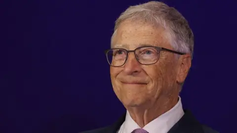 Bill Gates wearing a suit and glasses is pictured at an event at a hotel in New Delhi