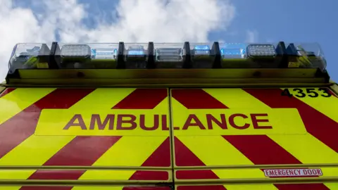 The back of a West Midlands Ambulance with blue flashing lights