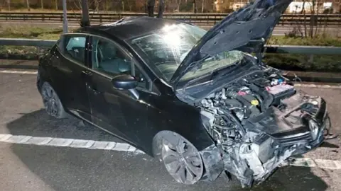 The mangled wreckage of a black car on the M8 after a drink-driver crashed his car in Glasgow and was caught after fleeing the scene wearing only one shoe