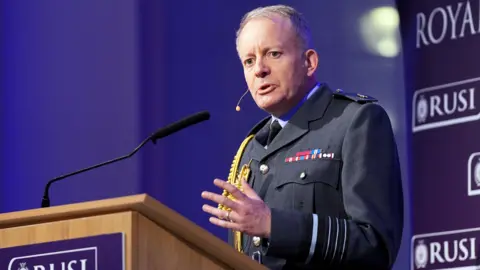 Sir Richard Knighten speaks at a podium. He is wearing military uniform 
