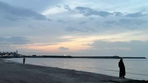 A woman stands on a Caspian Sea beach in Iran