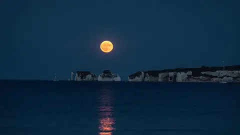 Hang Ross Another shot of the same rock formation from further back. The moon is higher in the sky, casting an orange reflection across the sea.