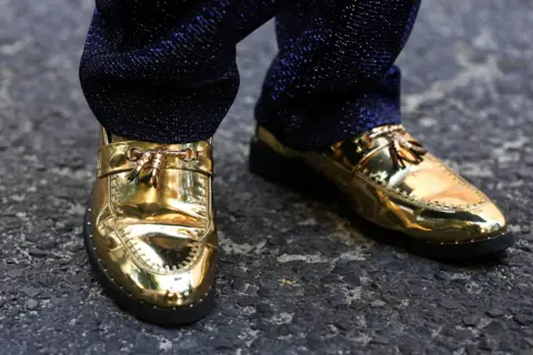 Nick Bothama / Reuters A close-up image of shiny gold shoes.