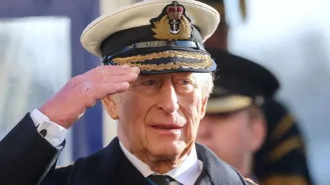 Chris Jackson/Getty Dressed in a naval jacket and cap with gold brad King Charles salutes.