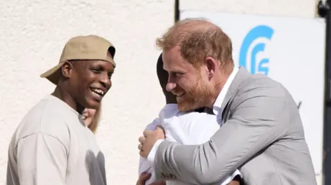 Rueters Prince Harry hugging a man, next to another smiling man