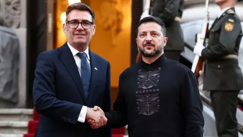 Burnham and Zelensky pose looking at the camera while shaking hands with soldiers behind them, on the steps of Horodetskyi House in Kyiv on Monday.