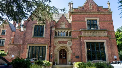 Cheadle Civic Society The gothic building - known as Abney Hall and Gardens - is made from red brick with sandstone details. 