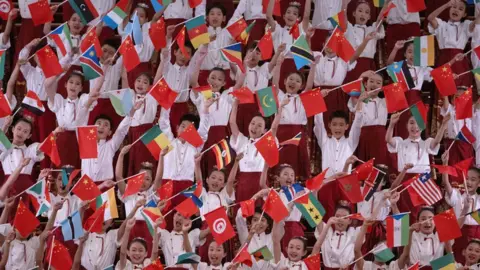 Andres Martinez Casares / Reuters Anak-anak Tiongkok mengibarkan bendera negara mereka di samping bendera negara-negara Afrika untuk menyambut para pemimpin Afrika di Beijing - Rabu 4 September 2024