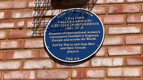 A blue plaque reads: Luton Heritage Forum/The FA. Chiltern Valley Ladies FC and British Independents (1967-1972). Pioneers of international women's tournament football in England, Europe and across the World. Led by Harry and June Batt and their female players.