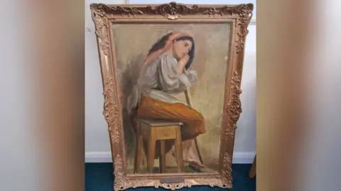 Leonard Cheshire A painting believed to be by artist Stanhope Alexander Forbes. It shows a woman sat on a stool leaning on a broom. It's a golden coloured frame in front of a white wall. 