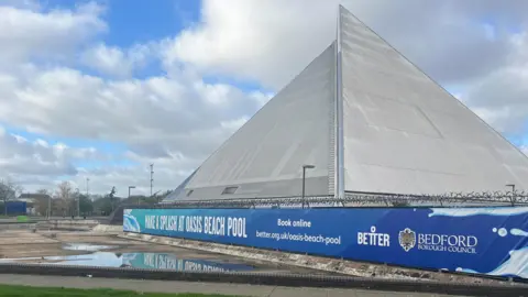 Tony Fisher/BBC A triangle shaped building with a large sign outside which reads "make a splash at Oasis Beach Pool".