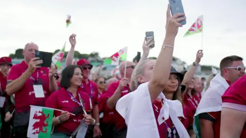 Ynys Môn's atheles, dressed in red, walking into the venue of the 2023 Island Games opening ceremony