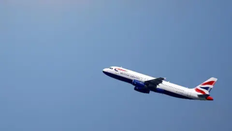 A British Airways Airbus A320 flies up through a blue sky.