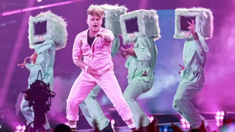 EPA Look No Computer performing on stage in a pink boiler suit