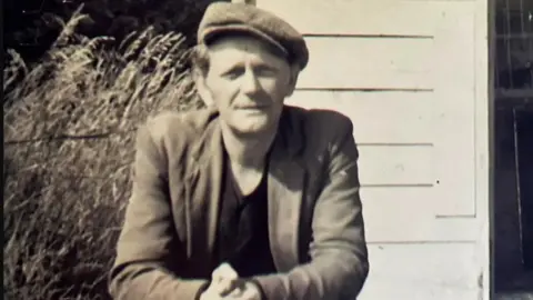 Nottinghamshire Police Black and white photo of 54-year-old Alfred Swinscoe wearing a flat cap and standing in front of his shed 