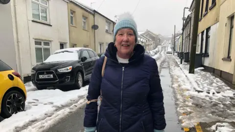 Kay Rees, pictured on a residential street covered in snow in Brynmawr, Blaeneau Gwent. 