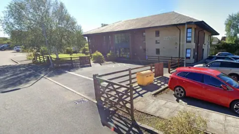Google A Google Street View screenshot of Temple Sowerby Medical Practice. It is a large building with multiple floors and a car park.