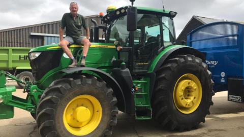 Richard Langton sat on a green tractor 