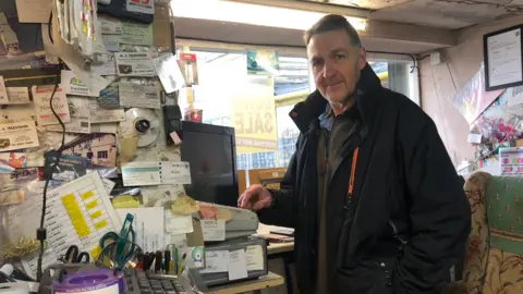 BBC / Naj Modak Melvyn Stroughair using the till in the shop