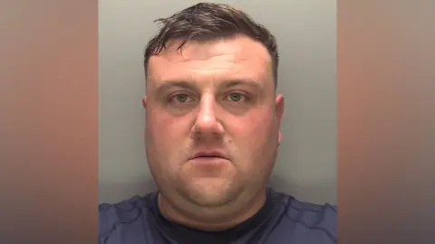 Lincolnshire Police Police custody photograph of Lathan Middleton. He has short dark hair and is wearing a blue top.