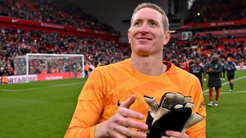 Chris Kirkland standing smiling on the pitch holding his goalkeeping gloves