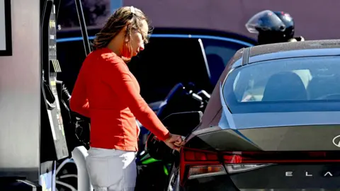 A woman pumps gas at an Exxon station in Washington, D.C. on April 7, 2026. 