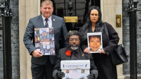 @TruthAboutZane Ian Murray, (left) from the Fire Brigades Union and Zane's parents Kye Gbangbola Nicole Lawler outside 10 Downing Street. Kye is holding a box full of signatures for a petition. Nicole is holding a photo of Zane.