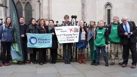 PA Media A group of people in a line holding signs. One reads "Friends of the earth".