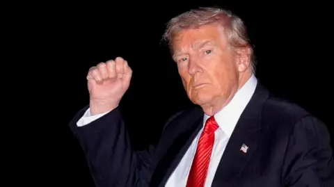 Reuters Mid-shot of Donald Trump wearing a red tie and raising his fist 