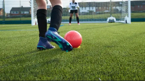 Children playing football on a synthetic pitch