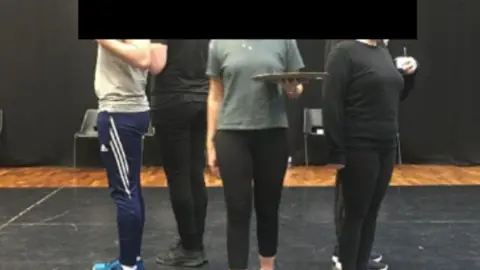 AFCF / FREEDOM OF INFORMATION Three anonymous people standing in a performance space in a theatre.