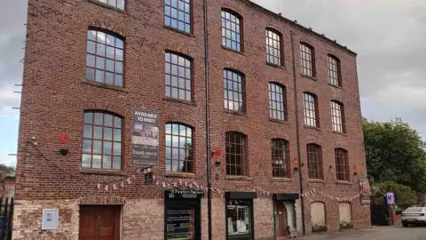 Martin Cove The mill building before the fire - bunting can be seen displayed across the red-brick facade.