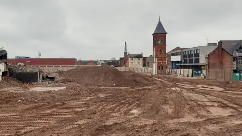 Stafford Borough Council The image shows the cleared site of the former Guildhall Shopping Centre. Buildings are in the background.