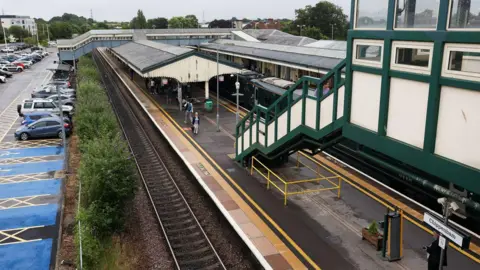 GWR View of Chippenham station from one of the bridges - platforms in view, train pulled into one and to the left the car park unaffected by the latest work.