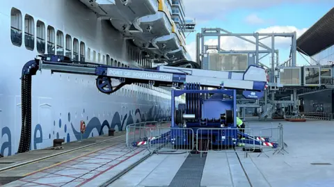ABP A crane-like arm extends from a quayside power unit to connect with a berthed cruise ship in Southampton.